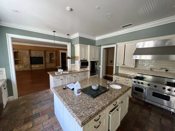 Before: white painted kitchen with speckled stone counters, a stainless range hood and a brick-look tile floor, Lake Sherwood
