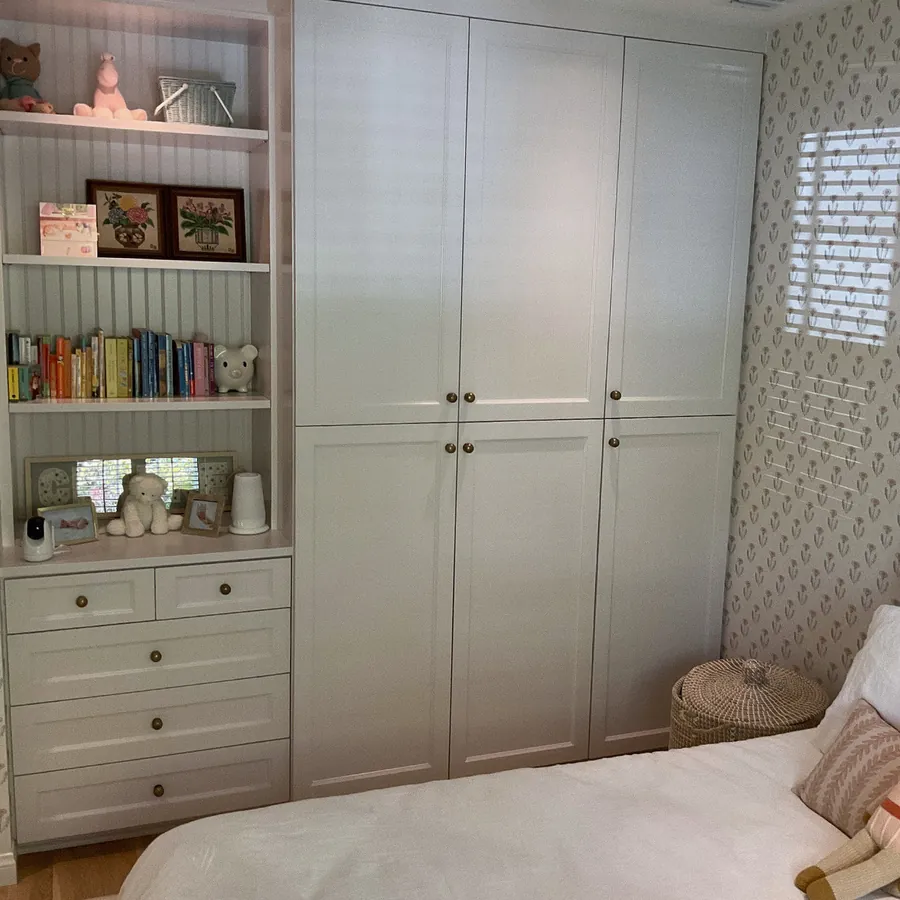 White shaker closet wall with a built-in bookcase and drawer base in a bedroom