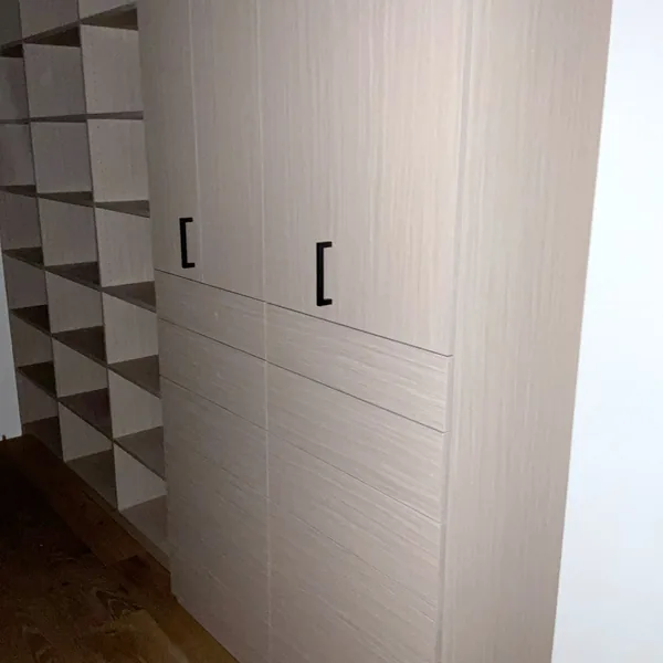 Oak-look wardrobe doors with black pulls over drawers, next to a wall of open cubbies