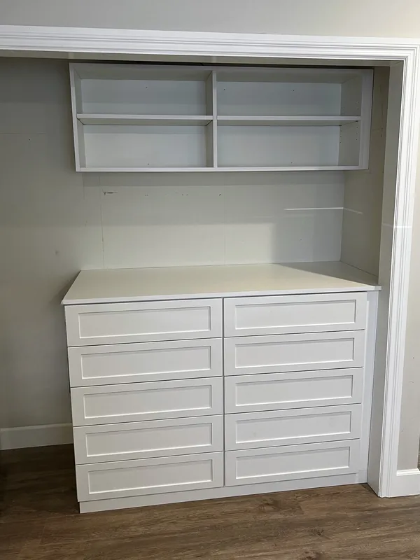 Reach-in closet with a white eight-drawer built-in dresser and open white shelving above, Thousand Oaks