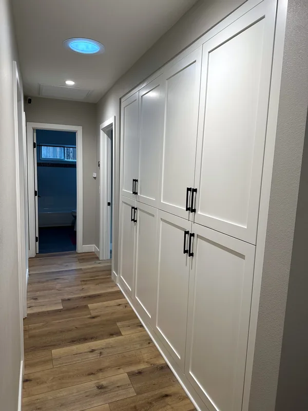 Hallway lined with floor-to-ceiling white shaker wardrobe doors with black pulls, Thousand Oaks