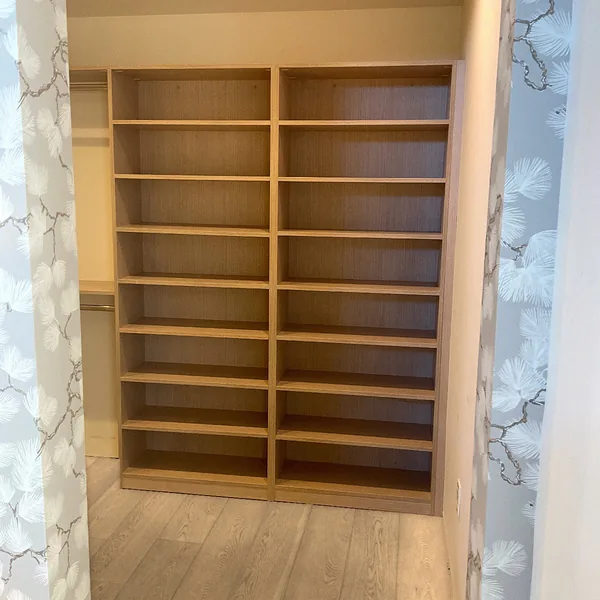 Straight-on view of a tall oak-look adjustable shelving wall
