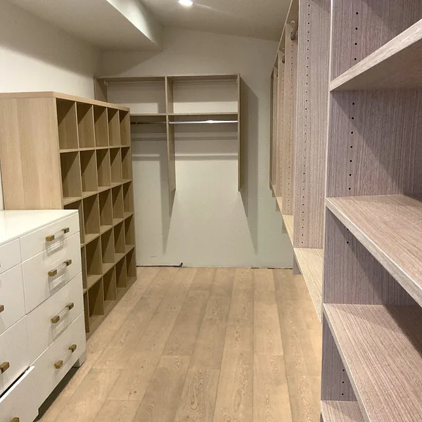 Walk-in closet with a white drawer bank, shoe cubbies, double hanging and shelving