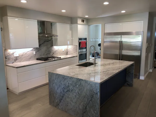 Gloss white kitchen with a navy island and a stone waterfall countertop, Simi Valley