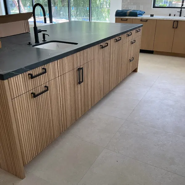 Modern kitchen island with fluted wood cabinet fronts and a dark countertop