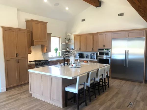 Light oak shaker kitchen with a large quartz-topped island, a range hood, tall pantry cabinets and a paneled refrigerator wall, Santa Rosa Valley