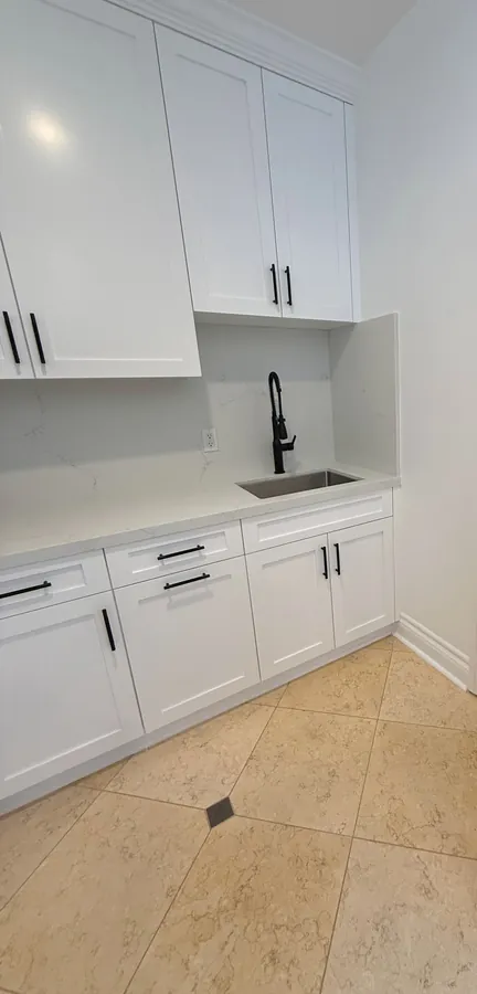 White shaker laundry room with upper cabinets and a base cabinet with a sink