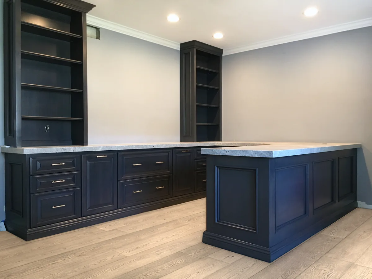 Navy home office with an L-shaped desk run, a peninsula and two bookcase towers
