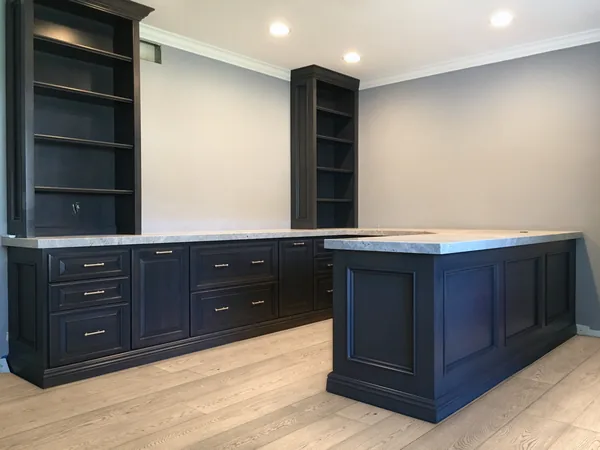 Navy home office with an L-shaped desk run, a peninsula and two bookcase towers