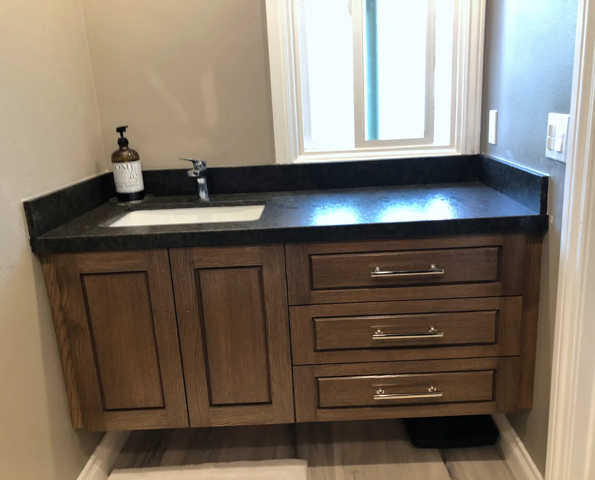 Stained wood vanity with drawers and a dark stone top, Thousand Oaks