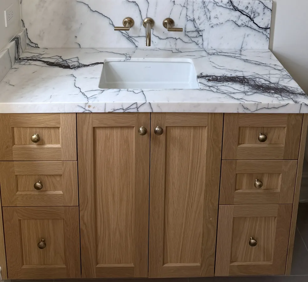 Oak shaker vanity with brass knobs and a dramatic veined stone top, Thousand Oaks