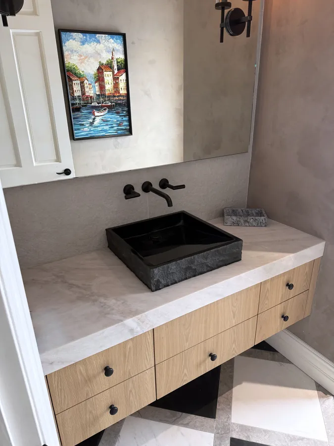 Floating oak vanity with a black vessel sink and a white stone top, Thousand Oaks