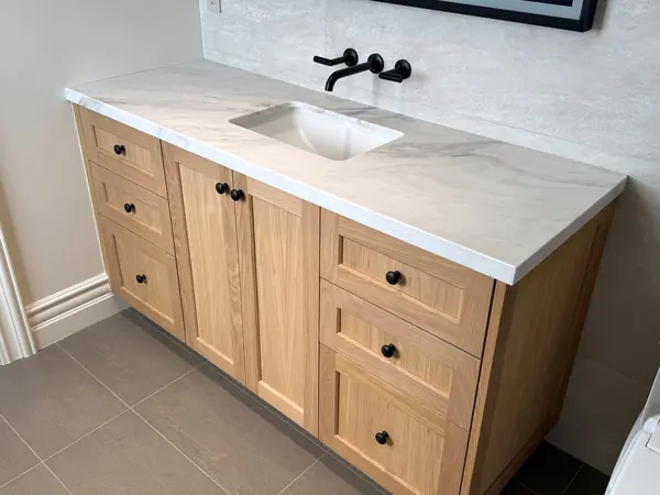 Oak shaker vanity with black knobs and a white stone top, Thousand Oaks