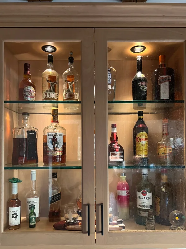 Close view of a light oak bar cabinet with glass doors and lit glass shelves, Santa Rosa Valley